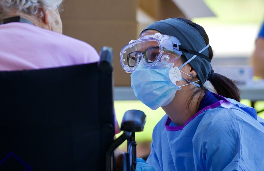 Jennifer Romero, a registered nurse with the Florida Department of Health, explains the process of the specimen collection to a nursing home resident in Northeast Florida, May 1, 2020. (Photo by Sgt. Michael Baltz, “Florida National Guard,” CC BY 2.0)
