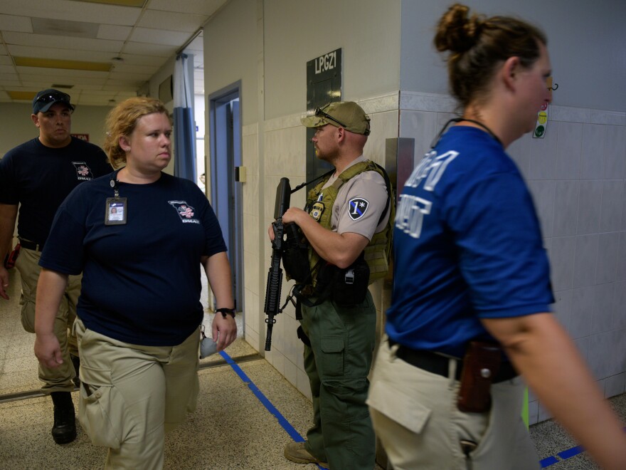 The U.S. Disaster Medical Assistance Team (DMAT) inspects a damaged hospital in Aguadillo, Puerto Rico, with a federal agent providing force protection.