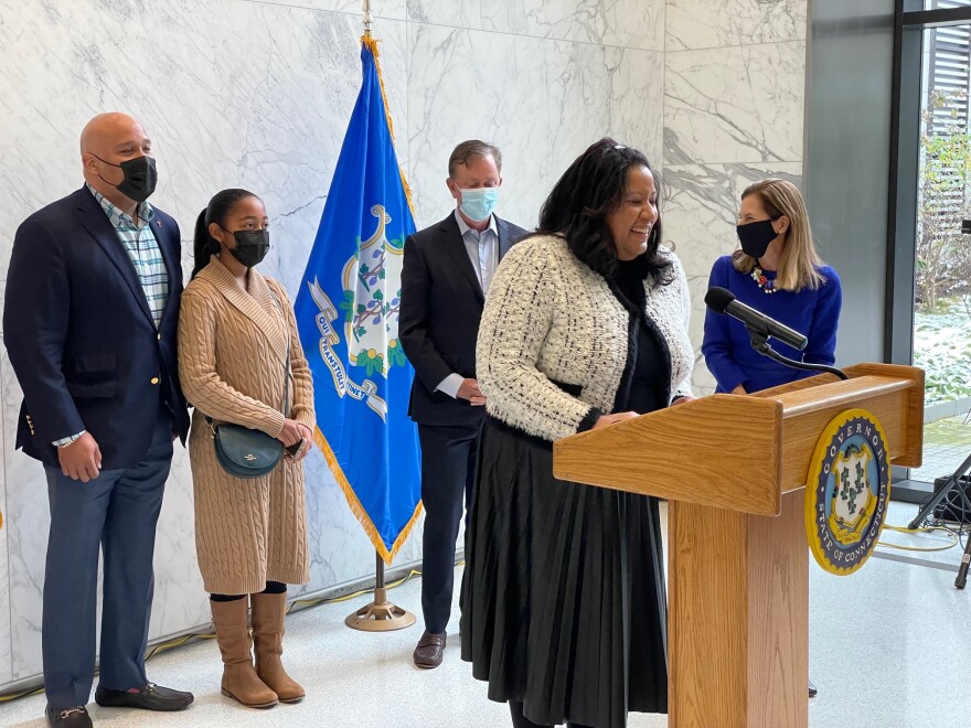 Natalie Braswell, at the podium. Behind her, from left are: her husband, Robert; their daughter, Gabby; and Gov. Ned Lamont and Lt. Gov. Susan Bysiewicz.