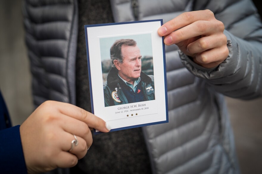 Grace Rector and Yuri Nesen, both sophomores at Georgetown University, hold up a card commemorating former President George H.W. Bush after visiting the Capitol.