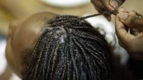 A woman gets her hair braided. (Charlie Riedel/AP)