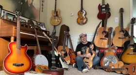 Lee Dellapina surrounded by more than a dozen guitars.
