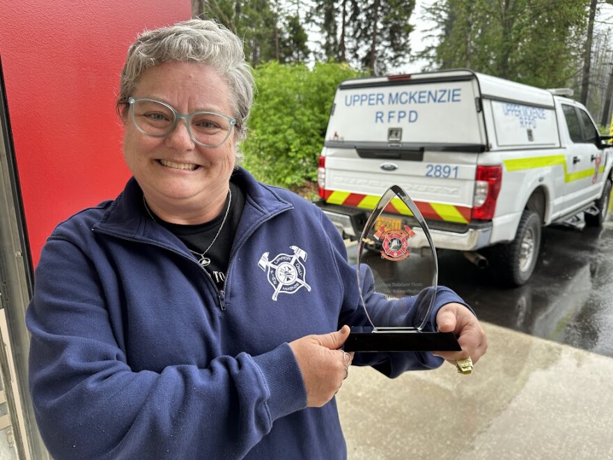 Christiana (Chief Rainbow) Plews holds a commemorative plaque honoring her service as a fire chief, shortly after her retirement this year. She and her fellow firefighters battled the Holiday Farm Fire when it swept through Blue River on Labor Day, 2020.