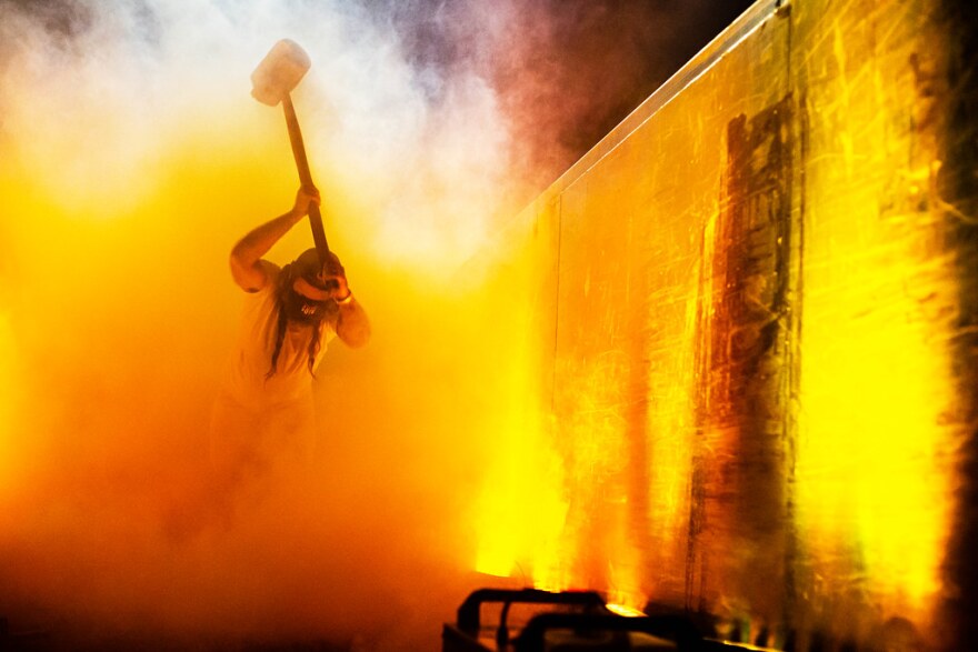 A person bangs a hammer on a dumpster.