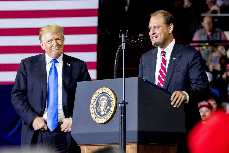 In this Oct. 13, 2018 photo, President Donald Trump, left, listens as Rep. Andy Barr, R-Ky., right, speaks at a rally at Alumni Coliseum in Richmond, Ky. The Lexington-area battle pits third-term Republican Rep. Andy Barr against Democrat Amy McGrath, a retired Marine fighter pilot. Trump won the 6th District by more than 15 percentage points in 2016. But with the help of carefully-shaped campaign ads that went viral, McGrath holds the edge on campaign fundraising.
