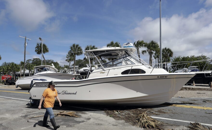 A woman walks past pleasure boats that were washed into Riverside Dr., when Hurricane Hermine came ashore early Friday, Sept. 2, 2016, in Steinhatchee, Fla. Hermine was downgraded to a tropical storm after it made landfall, as it moves over Georgia, but the U.S. National Hurricane Center says winds are increasing along the Southeast coast and flooding rains continue.(AP Photo/Chris O'Meara)