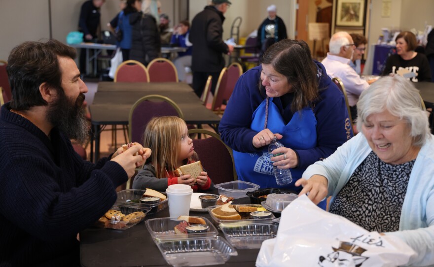 Three-year-old Claude talks to his aunt, Michala Chipurnoi, Sarasota, as he watch lunch with his father, Nicholas Morganti, Maryland, and Grandmother, Martha Magenheim, Sarasota and original member of the Temple. The 18th Annual Jewish Food Festival at Temple Sinai in Sarasota was held this Sunday, Feb 1, 2026. Brisket, pastrami and corned beef sandwiches were served by local restaurant Wolfie’s. As well as baked goods, matzoh ball soup, strudels and more.The Temple served up a celebration of flavors and traditions of their community.