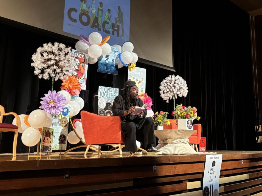 Writer on a stage expressively reads to an auditorium.