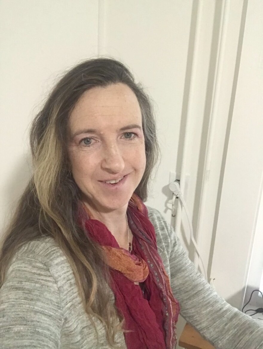 A woman with long hair smiles toward the camera in a selfie.