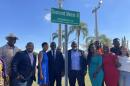 A group of people stand next to a street sign