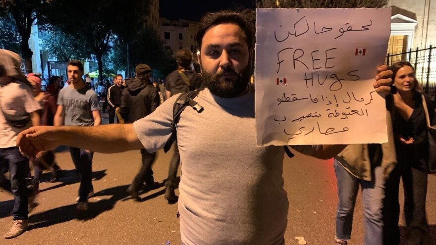 Mahmoud Aswany holds a sign in Beirut that reads, "Hurry up free hugs" — a dig at the government's attempts to raise revenue from taxes.