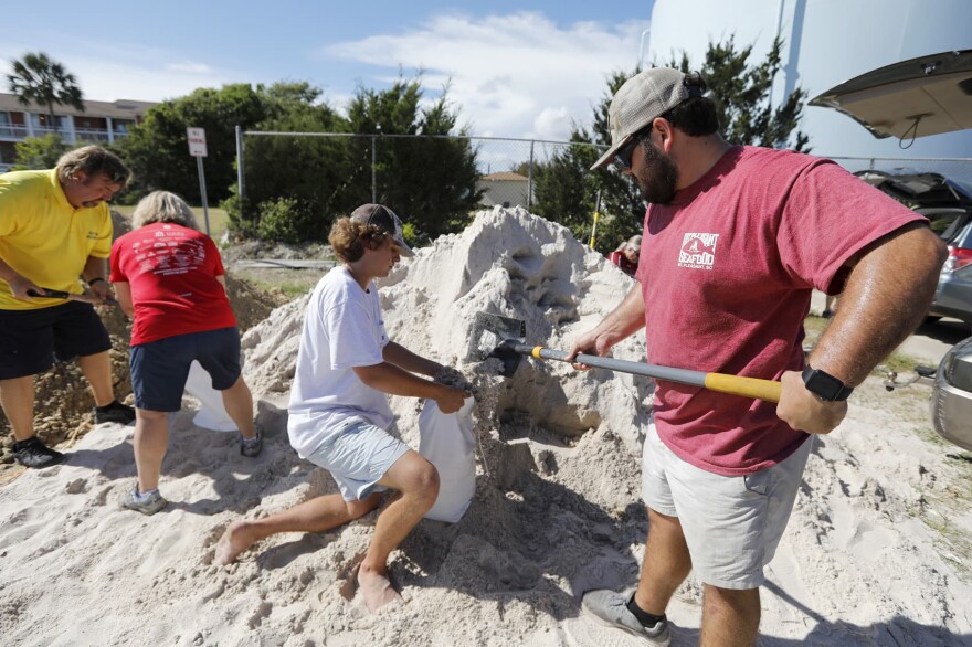 Walker Townsend, at right, from the Isle of Palms, S.C., fills a sand bag while Dalton Trout, in center, holds the bag at the Isle of Palms municipal lot where the city was giving away free sand in preparation for Hurricane Florence at the Isle of Palms S.C., Monday, Sept. 10, 2018. (AP Photo/Mic Smith)