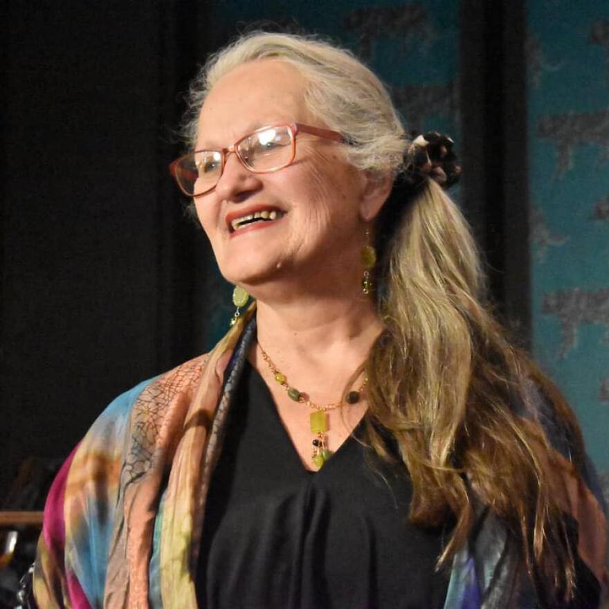 Laverne Zabielski looks away from the camera. She smiles and wears glasses and a colorful shirt.