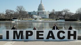People gather at the base of the U.S. Capitol with large IMPEACH and REMOVE letters in Washington, DC.