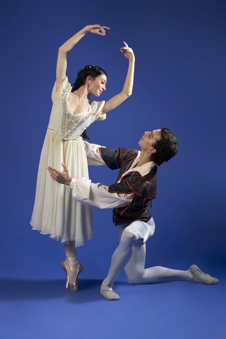 A male ballet dancer on one knee looking up at a ballerina