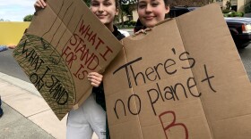 Alexandra Sasha Grieb and Kyleigh Dabler, both 19, from Kennewick, waved at passing cars driving by Richland’s John Dam Plaza. Grieb said it will be up to younger generations to fight climate change now with their votes. “The earth will survive climate change. Humans won’t,” she said. CREDIT: Courtney Flatt/NWPB