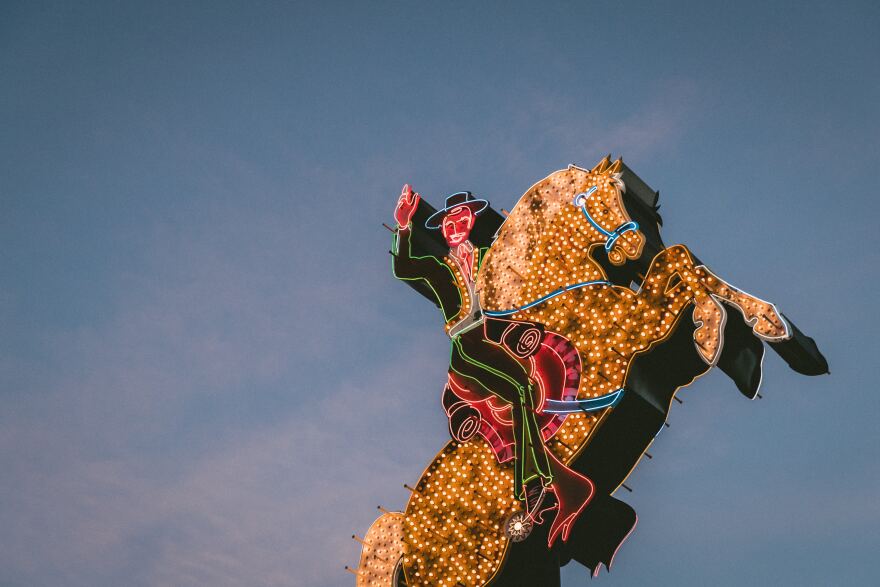 A huge, brightly lit neon sign of a horse and its rider stands tall on Fremont Street in Las Vegas. 