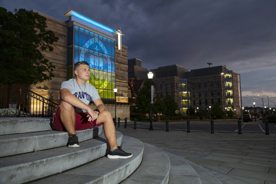 Serhii Kuzmin Jr. sits outside the University of Scranton's Gateway sign