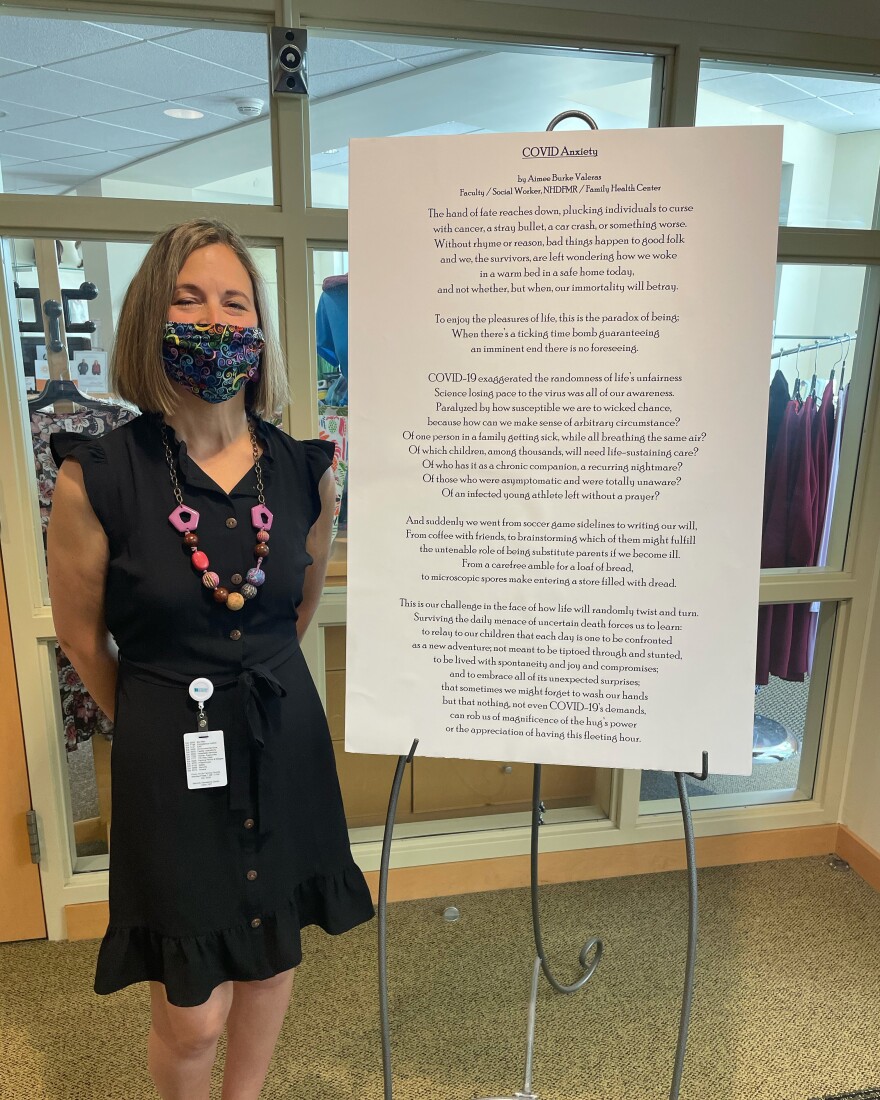 Aimee Valeras, who helped coordinate the event, stands next to her poem COVID Anxiety.