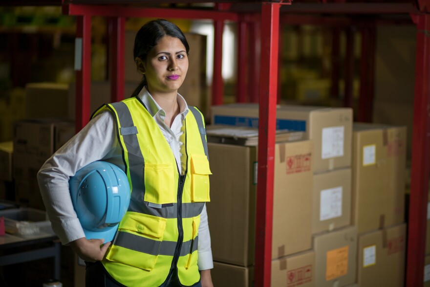 female warehouse worker with helmet and safety vest.