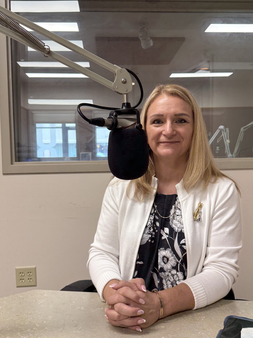 A woman seated at a microhpne in a radio studio.