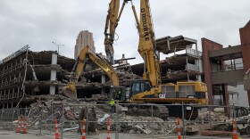 Two large backhoes sit atop concrete rubble.