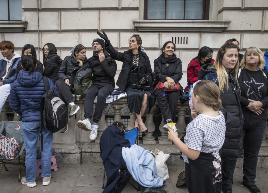 Farzana Khan, center, was among mourners gathering to say goodbye to Queen Elizabeth II outside of the Palace of Westminster and the houses of parliament on Monday. Even after lining up for 13 hours to see the queen, and seeing her coffin at multiple mourning events, Khan says it wasn't until she picked out her handbag last night that she teared up, thinking about the end of "feminine reign."