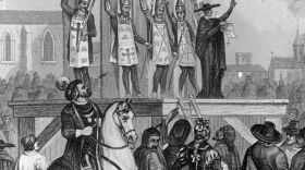 An illustration shows heretics being tortured and nailed to wooden posts during the first Inquisition.