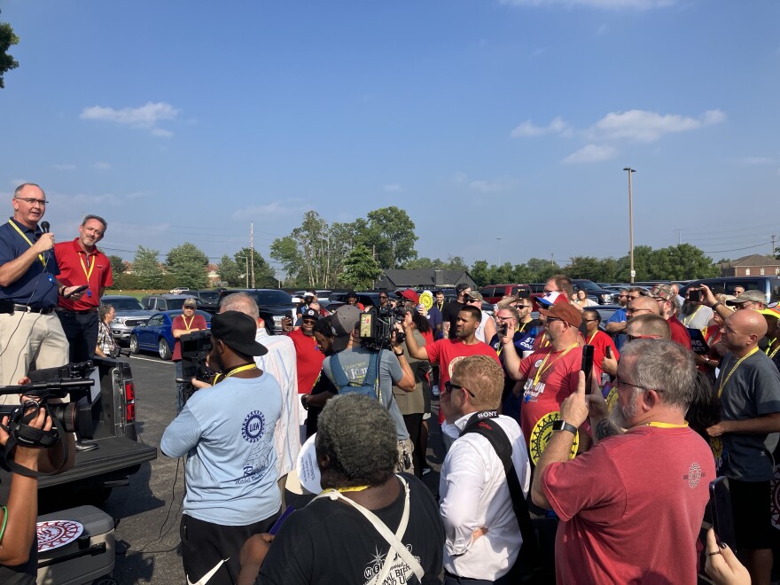 Two man stand in a pickup truck bed and speak to a crowd of supporters