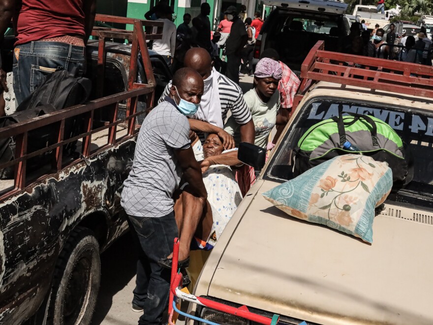 Residents carry an injured person through the streets in Les Cayes, Haiti, on Aug. 16.