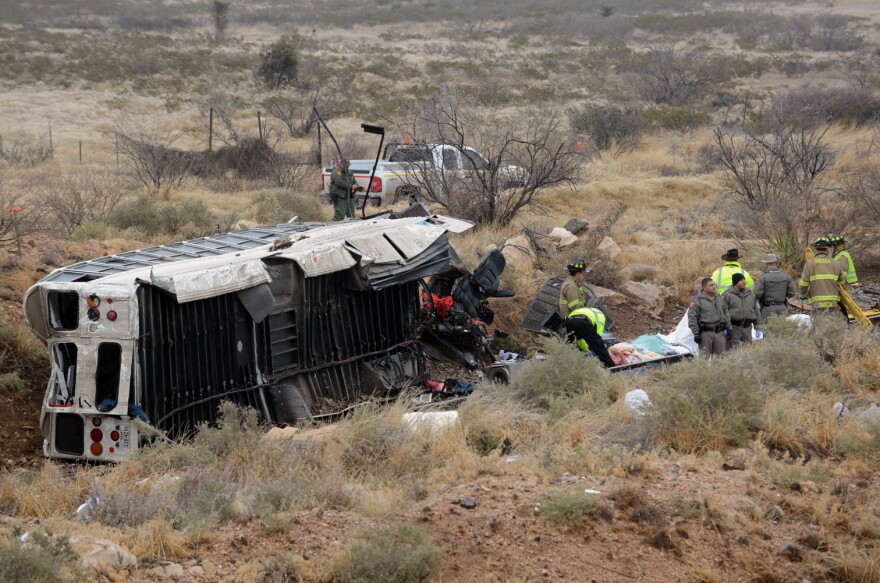 Officials investigate the scene of a prison transport bus crash in Penwell, Texas on Wednesday. Law enforcement officials said the bus carrying prisoners and corrections officers fell from an overpass in West Texas and crashed onto train tracks below, killing at least 10 people.