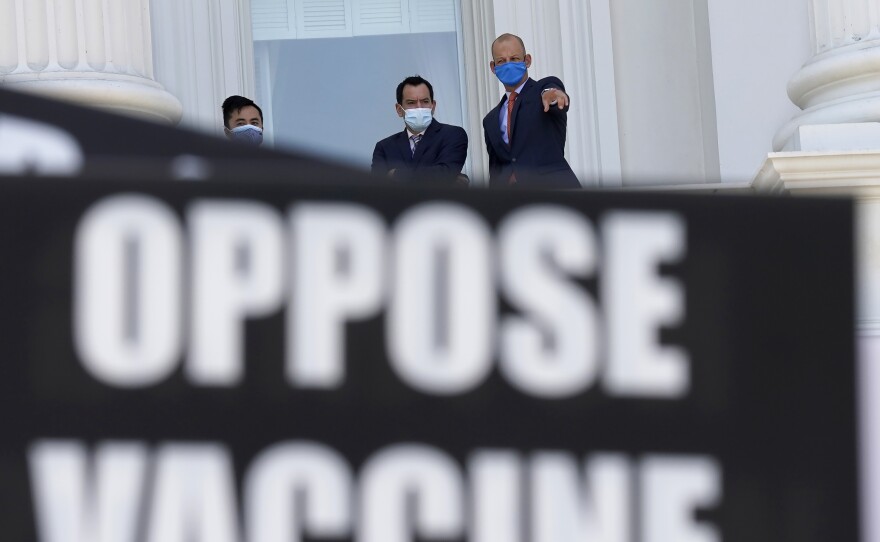Assembly Speaker Anthony Rendon of Lakewood (center) and Assemblyman Kevin McCarty, D-Sacramento, (right) watch from the balcony outside the Assembly Chambers as protesters opposing vaccine mandates gather at the Capitol in Sacramento, Calif.