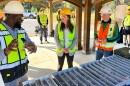 Woman and men in safety vests talk outdoors