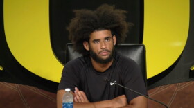 A man sits at a table in front of a microphone