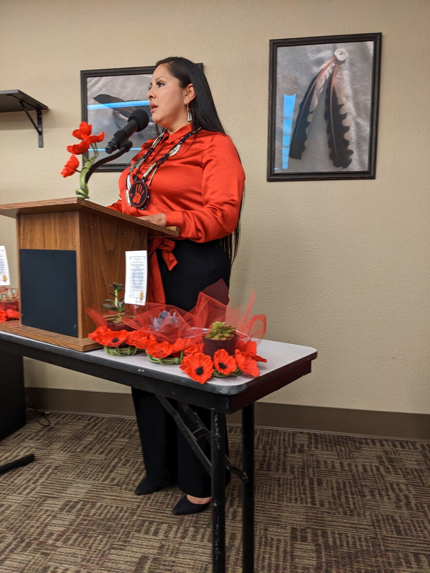 A woman wearing red stands at a podium.