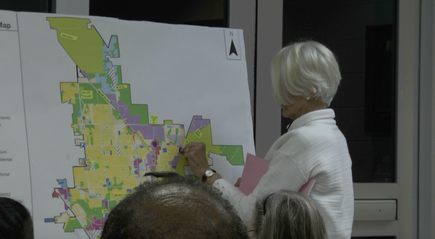 A resident places a marker on a future land-use map as she shares feedback on housing and transportation priorities during a recent planning workshop.