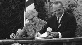 President Lyndon B. Johnson signs the ESEA in 1965 with Kate Deadrich Loney, the President's first schoolteacher.