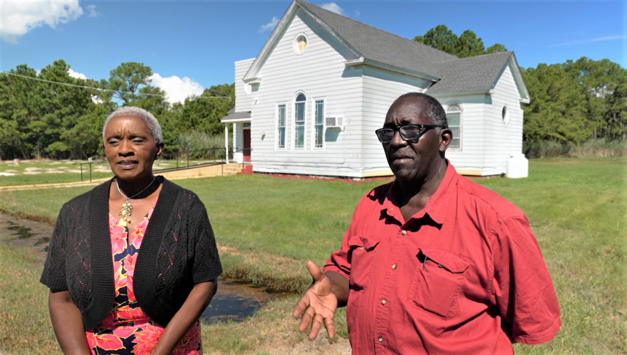 Claudia Wigfall (L), a Macedonia Church member and John E. Jones Jr, a singer at Macedonia church, discuss recurrent flooding that overtook the church and graveyard on Deal Island on Maryland’s southern Eastern shore. They appear in “Eroding History,” a documentary about how climate change is affecting Black communities on Deal Island, by Rona Kobell, Sean Yoes and André Chung. Photo: screen shot from documentary.