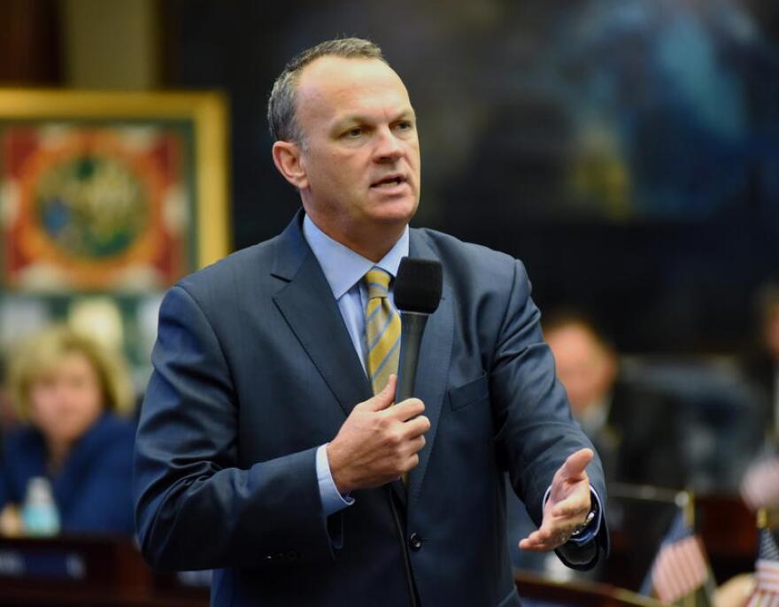 A man in a suit holds a microphone while he speaks. 