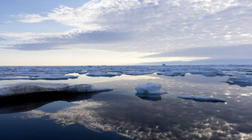 Cloud patterns and the midnight sun reflect over the Chukchi sea, where the summer sea ice floats in large slabs.