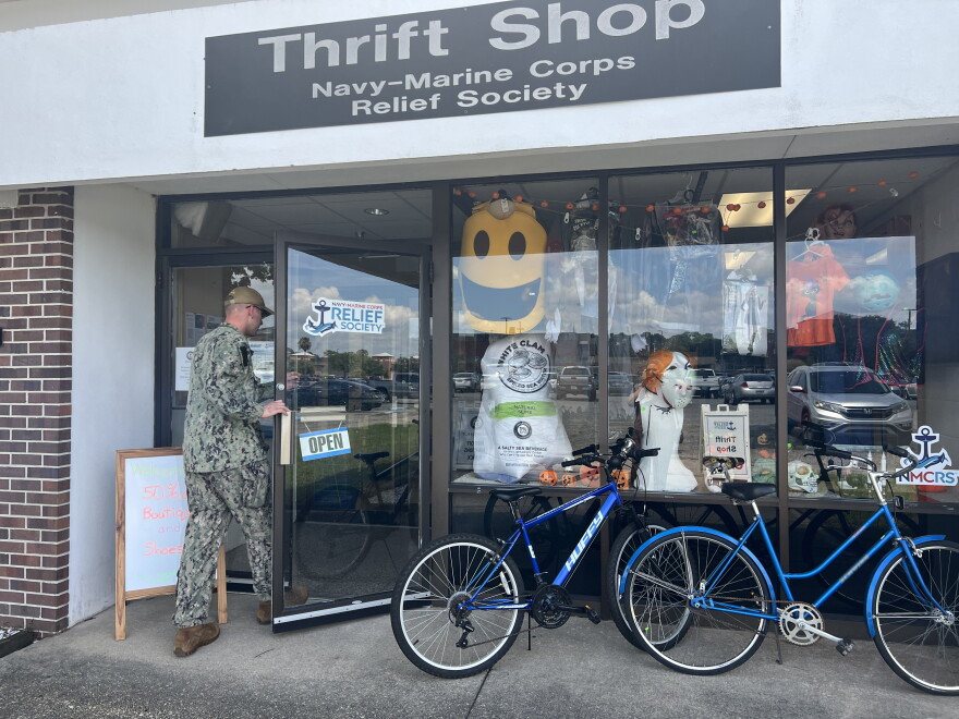 A service member enters the Navy‑Marine Corps Relief Society thrift shop, which offers a variety of secondhand goods. The shop supports charitable efforts for local military and their families.