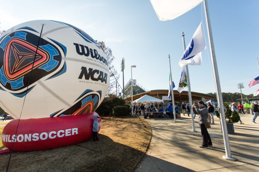 A young soccer fan poses for a photo in front of a giant inflatable soccer ball outside of WakeMed Soccer Park prior to the NCAA Women's College Cup final between Penn State and Duke in Cary, N.C., Sunday, Dec. 6, 2015. 