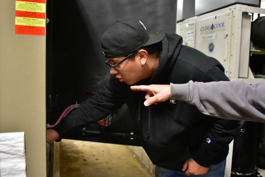 A maintenance high school apprentice with Indianapolis Public Schools works on a heating unit.