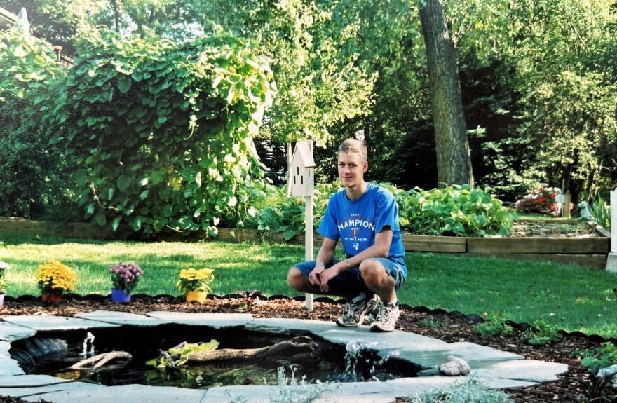 A young Dan Wanschura crouches next to a turtle pond in a suburban backyard.