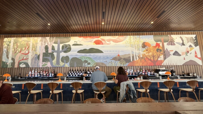 View of a restaurant bar with a painted nature mural above