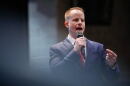 A man in a suit speaks into a microphone.