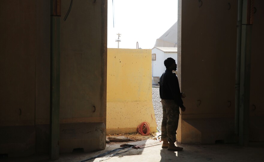 A U.S. service member stands in an entryway looking at some of the destruction from the missiles in the area where he used to live on the Ain al-Assad base. Wreckage included containerized housing units used by U.S. drone operators. They were destroyed when a ballistic missile hit a few hundred yards away.