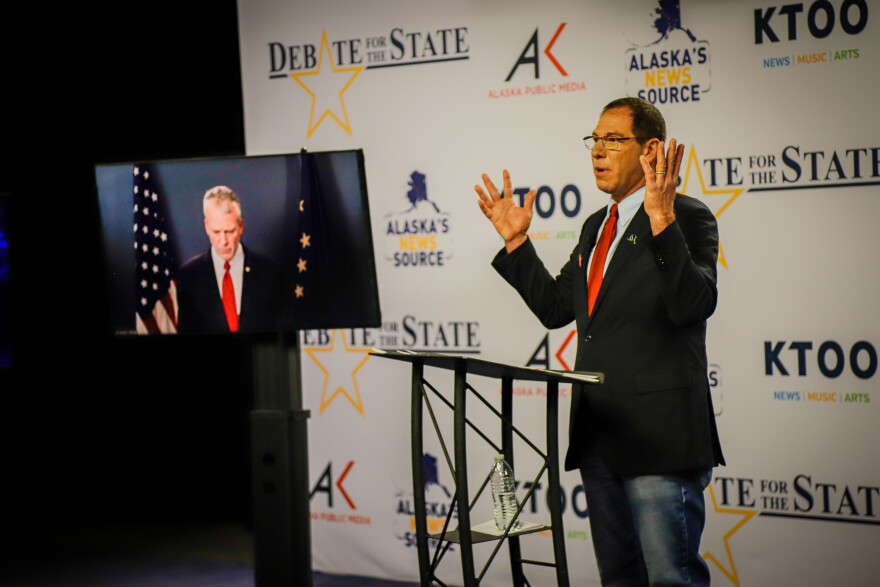 a person on a tv monitor and a person behind a podium with their arms up