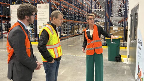 Erin Pulling, right, CEO of Food Bank of the Rockies, talks to U.S. Sen. Michael Bennet, middle, and Ron Meehan, government relations manager for Feeding Colorado in a large warehouse.