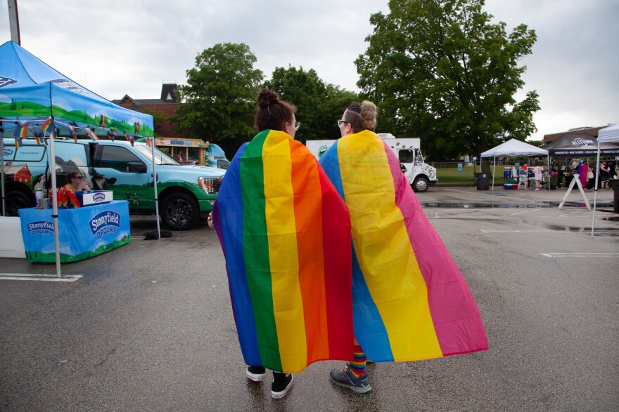 Two people with rainbow flags around their shoulders at a New Hampshire pride festival in June, 2023.